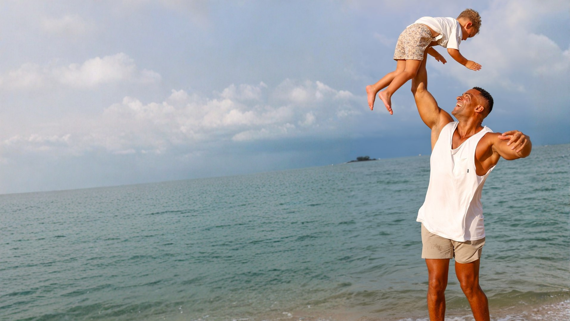 Vater hebt Kind am Strand